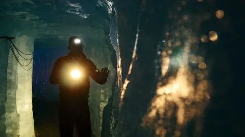 Male explorer discovering ice inside glacier cave tunnel holding flashlight Stock Footage 64799554