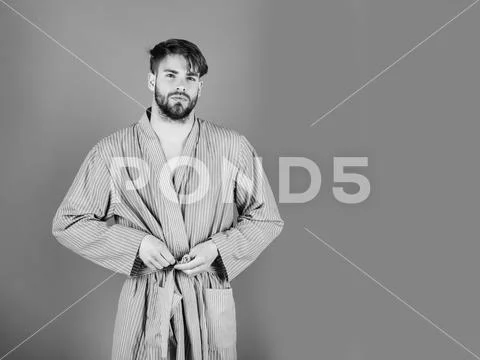 Male fashion, beauty and advertisement concept. Bearded man tying belt in bow on Stock Photos