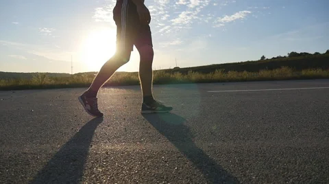 Male feet is walking on a rural road at sunset, slow motion, close-up Stock Footage