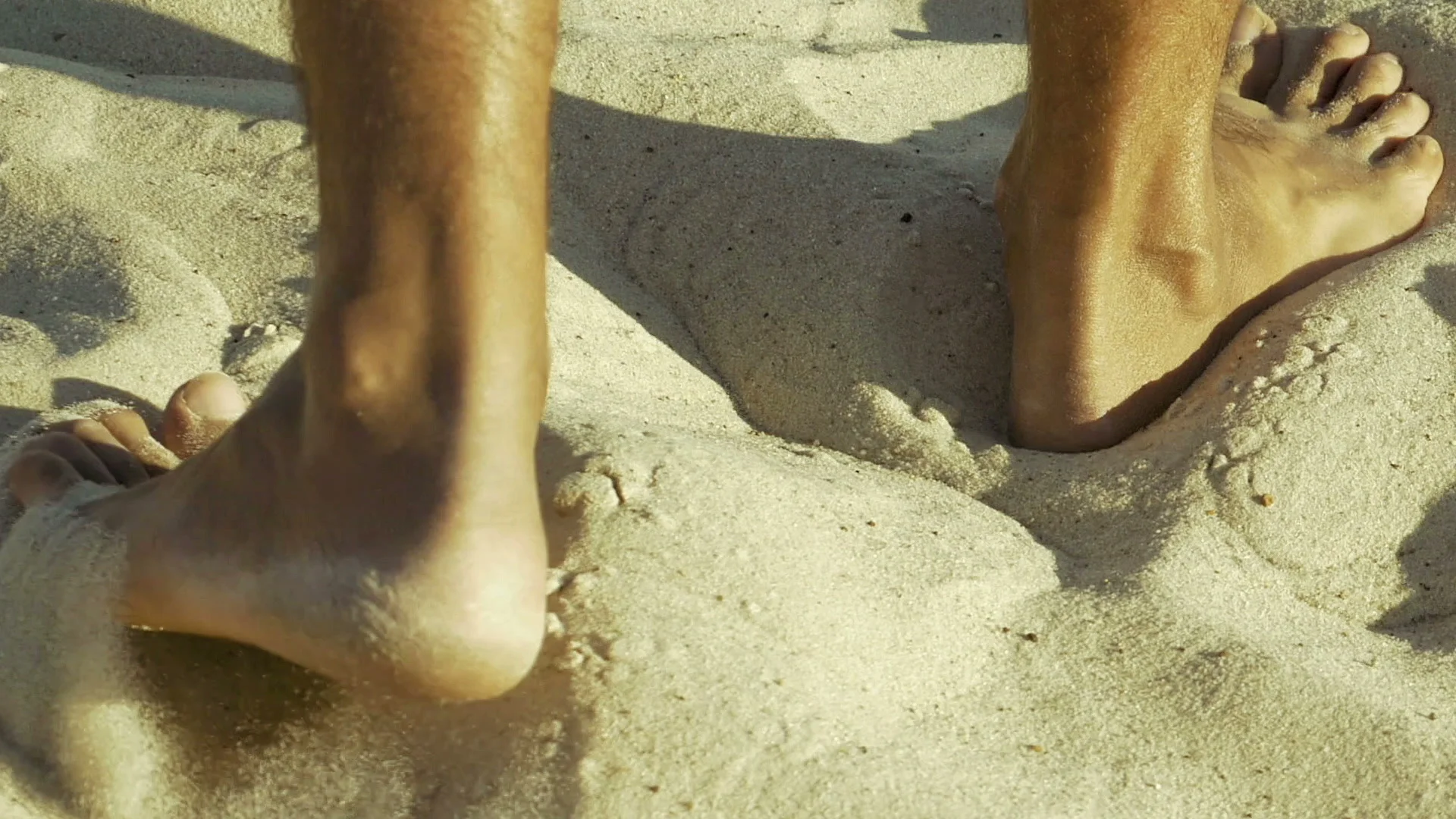 Male feet walking on sand