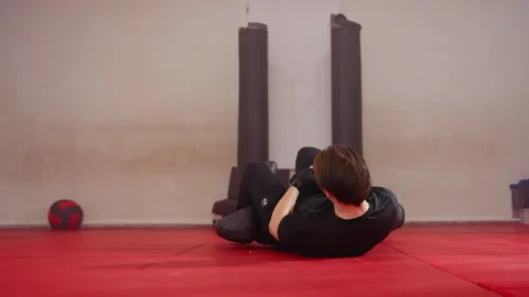 Male fighter practicing ground combat techniques in gym, wearing black Video stock 322539159
