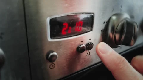 Male finger presses timer button on gas stove panel to set alarm, minutes. Man Stock Footage 344094364