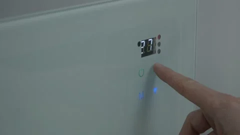 The male finger presses the touch button on the wall heater and adjusts the Stock Footage 235597838