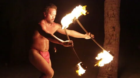 Male fire dancer walks forward juggling two fire rings, throws/catches Vidéo 68101468
