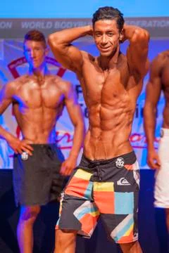 Male fitness model shows his physique in swimsuit om stage Stock Photos