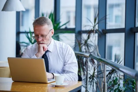Male freelancer is working in a cafe on a new business project. Sits at a lar Stock Photos