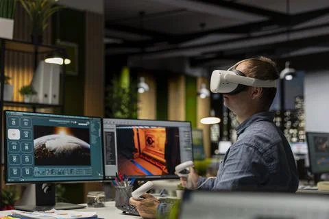 Male game developer using VR glasses and AI tech to design a spaceship 库存照片