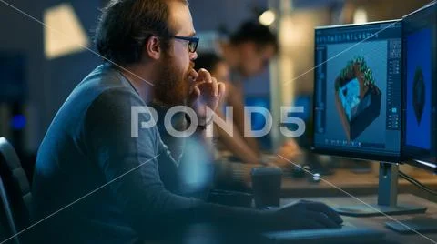 Male Game Developer works on a Level Design on His Personal Computer with Two Stock Photos