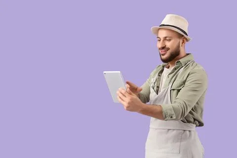 Male gardener using tablet computer on lilac background Stock Photos