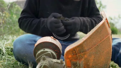 Male gardener winds string line on drum of electric lawn trimmer for mowing Video stock 130338377