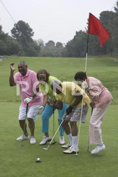 Male golfer watching ball approach cup Stock Photos