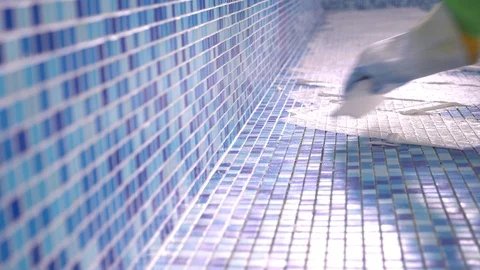 Male grouting newly installed ceramic tiles of swimming pool. construction of Stock Footage 89571747