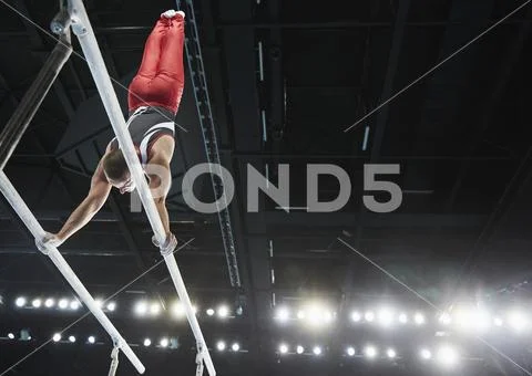 Male Gymnast Performing Upside-Down Handstand On Parallel Bars In Arena