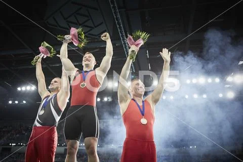 Male gymnasts celebrating victory cheering on winners podium Stock Photos
