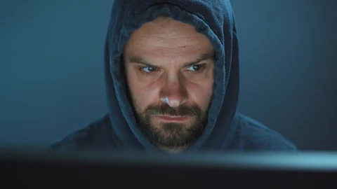 Male hacker in the hood working on a computer in a dark office room Stock Footage 121757467
