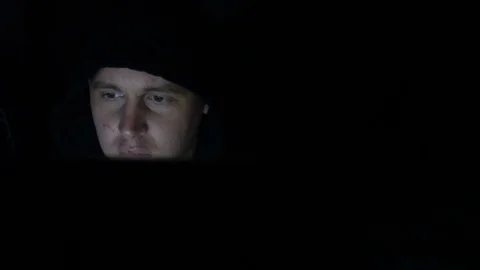 Male hacker working on a computer in a dark office room Stock Footage 77167164
