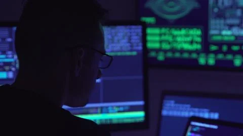 Male hacker working on a computer in a dark office room. Foto stock