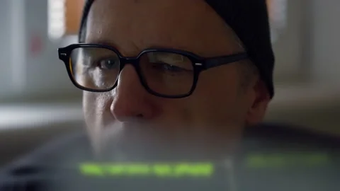 Male hacker working on a computer in shadowy light Stock Footage 167169602