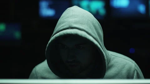 Male hacker working on a computer while wearing a hood so his face is hidden Stock Footage 59155895