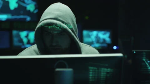 Male hacker working on computer while green code characters reflect on his face Stock Footage
