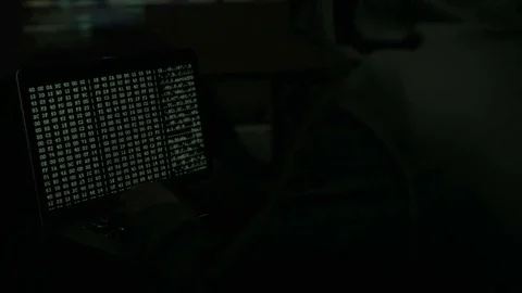 Male hacker working on a computer while green code characters reflect on his Stock Footage 84844723