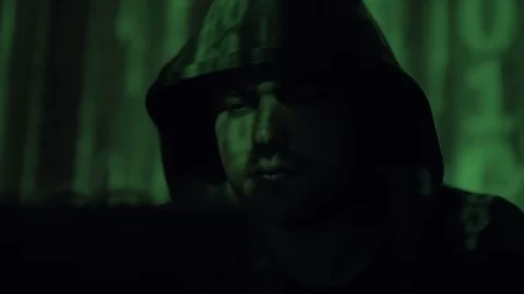 Male hacker working on a computer while green code characters reflect on his Stock Footage 84845415