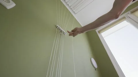 Male Hand Adjusting Strings Of Ceiling Mounted Clothes Dryer Rack Stock Footage 327953771