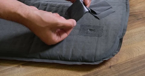 Male hand applying a repair patch on a mattress/sleeping mat and pressing on it. 스톡 동영상 112675535