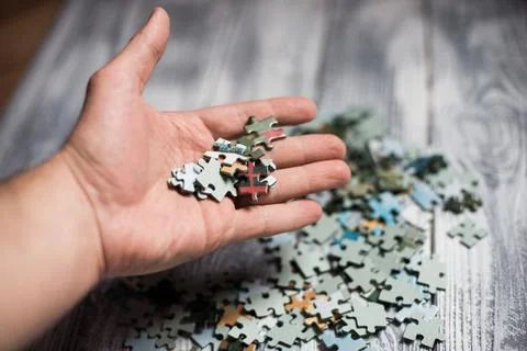 Male hand assembling a puzzle on the table Stock Photos