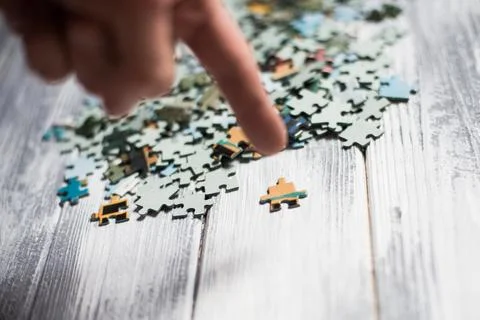 Male hand assembling a puzzle on the table Stock Photos