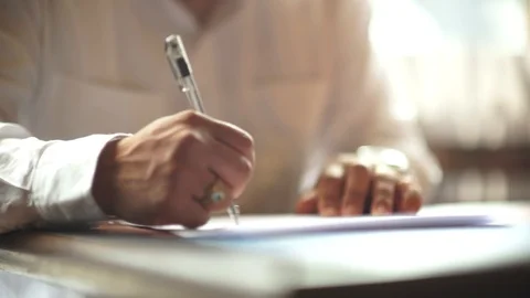 A male hand edits a printed document with a pen on a wooden table. Stock Footage 102371097