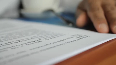 A male hand edits a printed document with a pen on a wooden table. Stock Footage 102371184