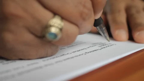 A male hand edits a printed document with a pen on a wooden table. Stock Footage 102371189