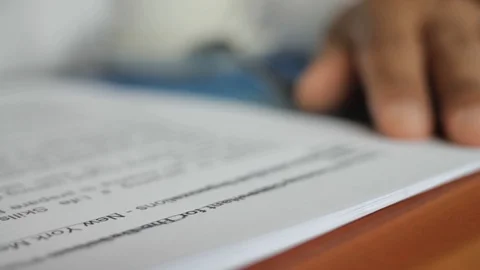 A male hand edits a printed document with a pen on a wooden table. Stock Footage 102371204