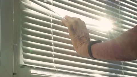 The male hand gently pulls back the blinds to discreetly watch what is Stock Footage 294701913