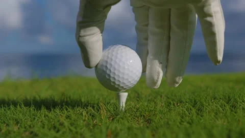 Male hand in a golf glove puts the ball on the field on the background of the Stock Footage