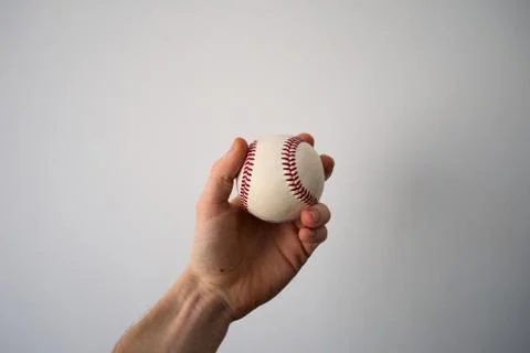 Male hand holding baseball ball on a background of white wall Stock Photos