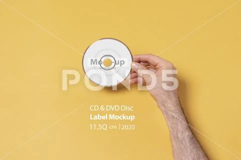 Male hand holding a CD-DVD disc in front of yellow background mock-up series PSD Template