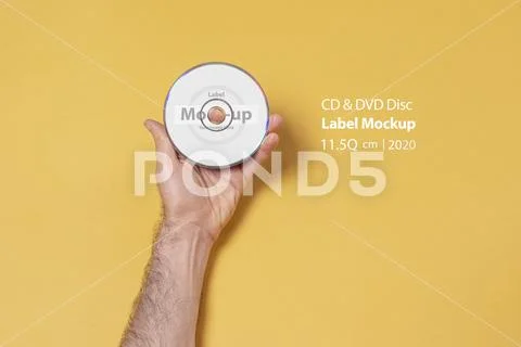 Male hand holding a CD-DVD in front of yellow background mock-up series PSD Template