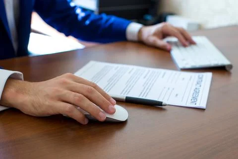 Male hand holding computer mouse with laptop keyboard in background 库存照片
