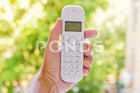 Male hand holding cordless landline telephone receiver outdoors Stock Photos