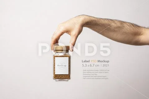 A male hand holding an instant coffee glass jar with blank label mock-up Plantilla PSD