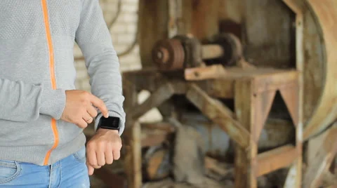 Male hand is holding a modern touch screen phone and blur image of old factory Stock Footage 65320239