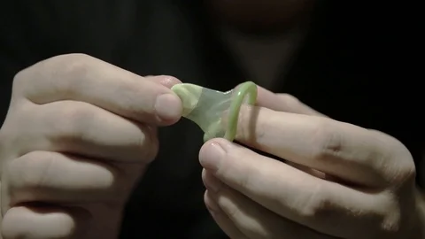 Male hand holding a new green condom and try to stretch it Stock Footage