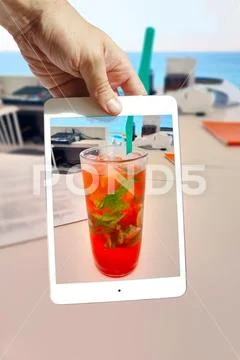 Male hand holding tablet ipad mini take photo of mojito cocktail Stock Photos