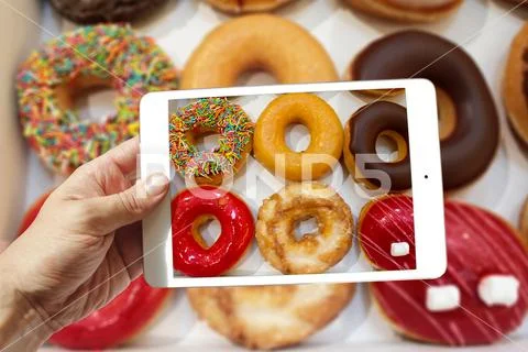 Male hand holding tablet ipad mini take photo of donuts box Stock Photos
