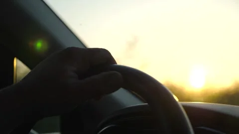 Male hand holds steering wheel while driving a motor car at sunset. Adult man Vídeo Stock 252669341