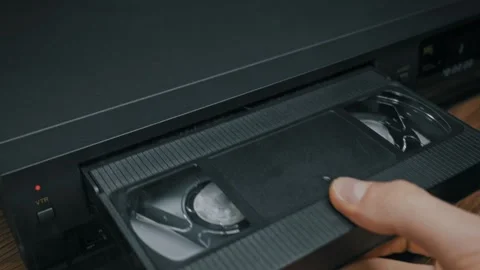 Male Hand Inserting Black VHS Tape Into Vintage VCR Player Deck Vídeos de archivo 329834961