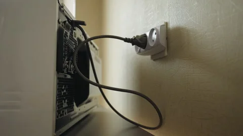 Male hand inserting plug of microwave oven into wall electrical outlet, setting Stock Footage 311053520