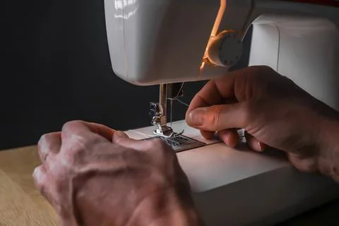 Male hand inserting thread into needle of sewing machine 写真素材